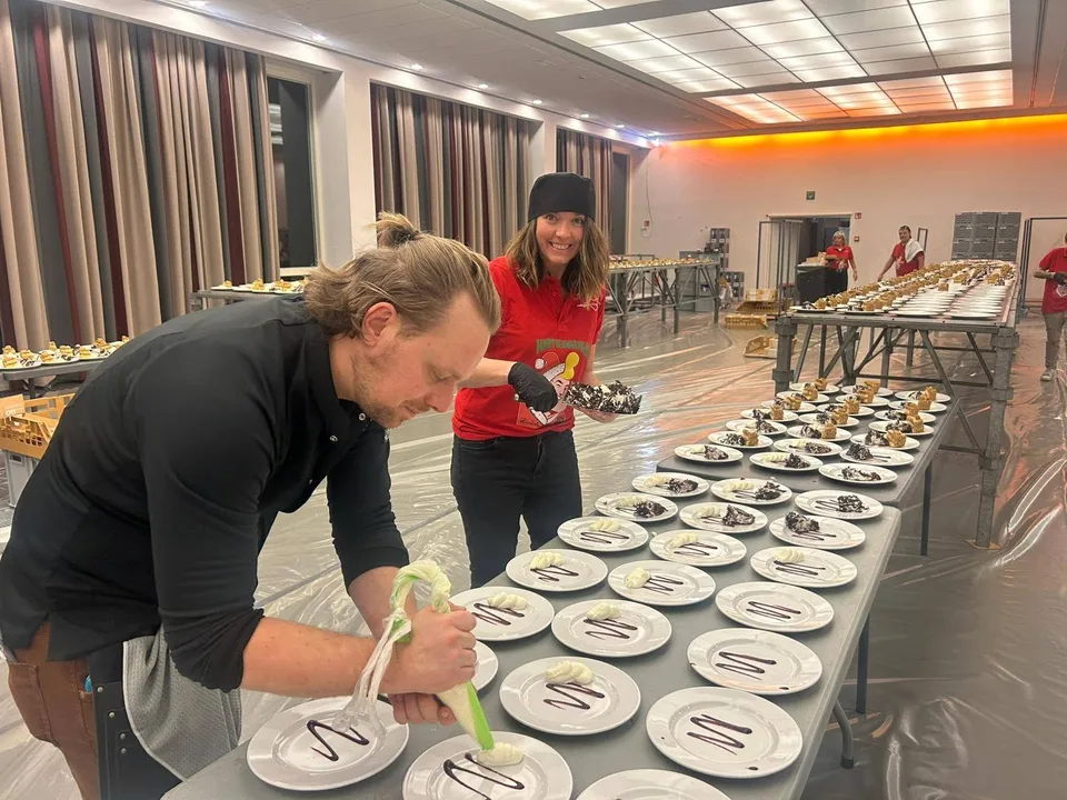 Vrijwilligers werken een reeks dessertborden af voor het kerstfeest van 2025.